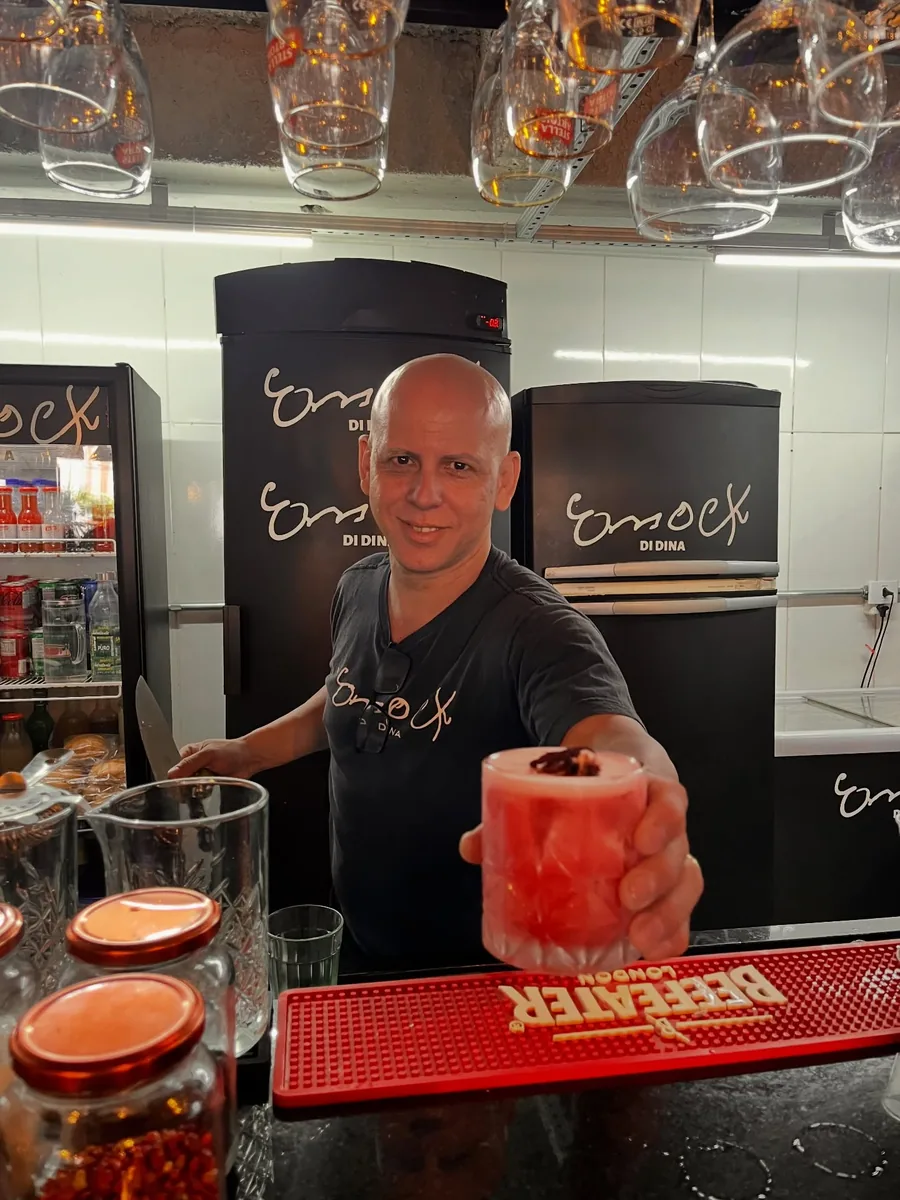 Atendente do balcão com dois cocktails vermelhos na mão