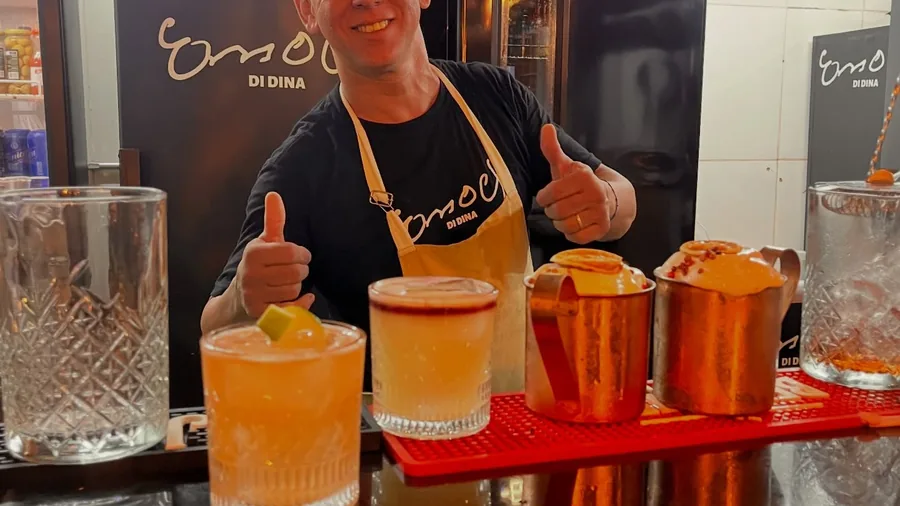 Atendente levando quatro cocktails coloridos para a mesa