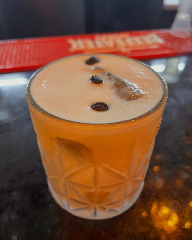 Drink com espuma servido em copo baixo, no balcão da casa