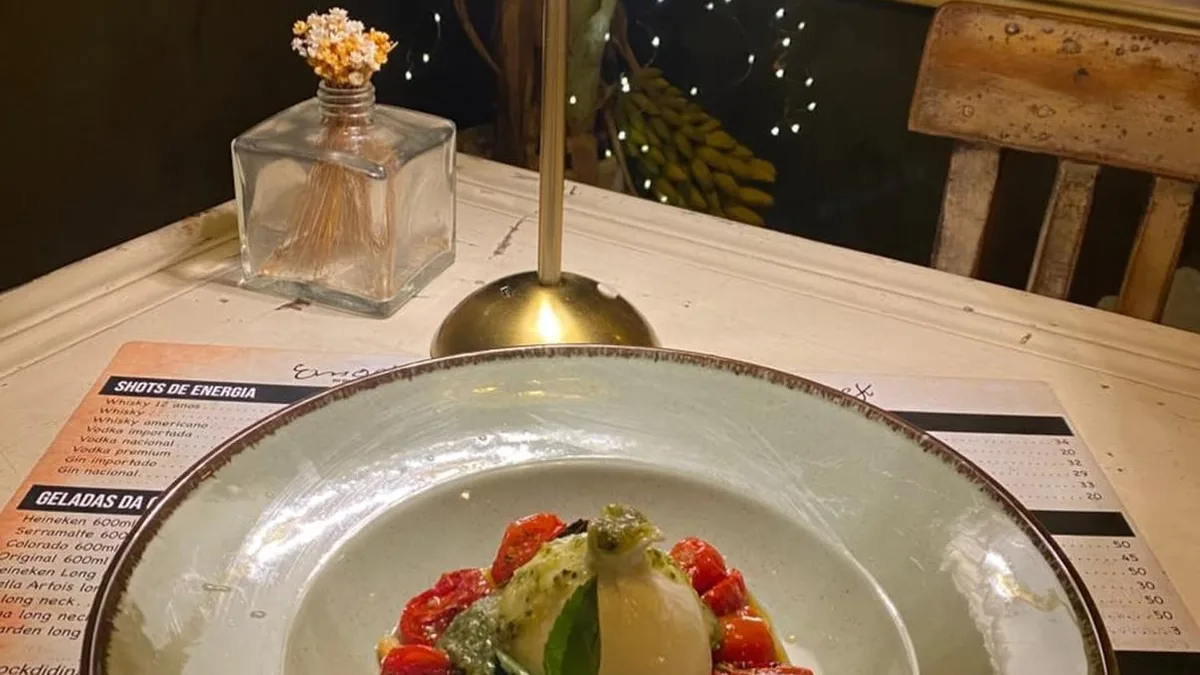 Mesa do salão com lamparina acesa e prato servido, à luz baixa da casa
